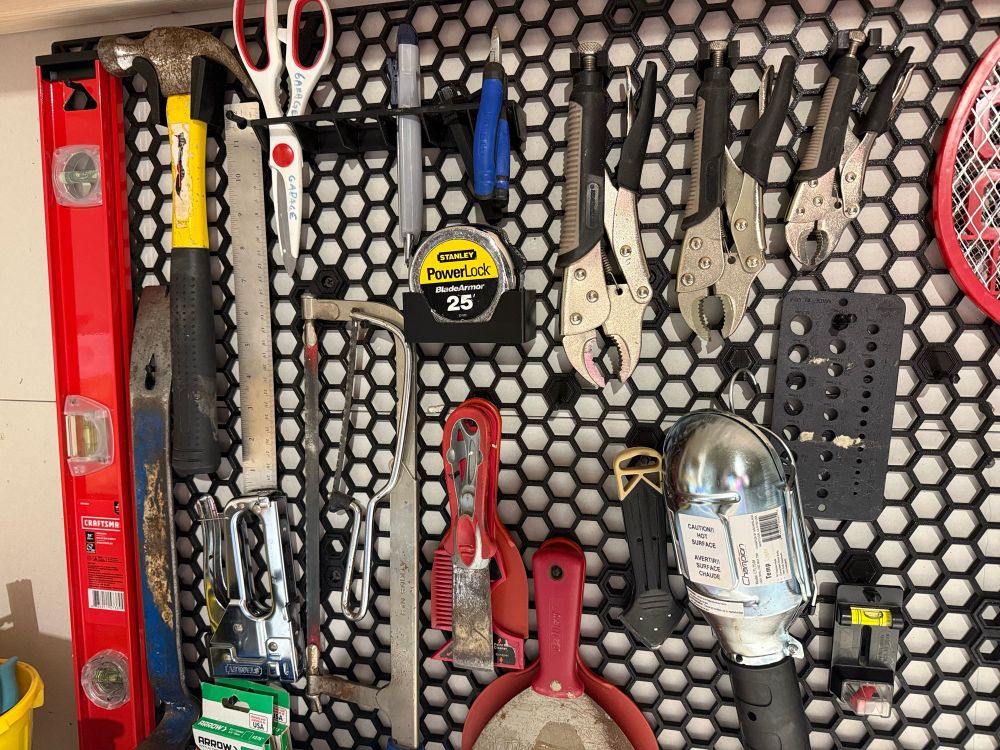 Hexagon storage wall with pegs and 3d printed tool holders with tools in a garage workshop 