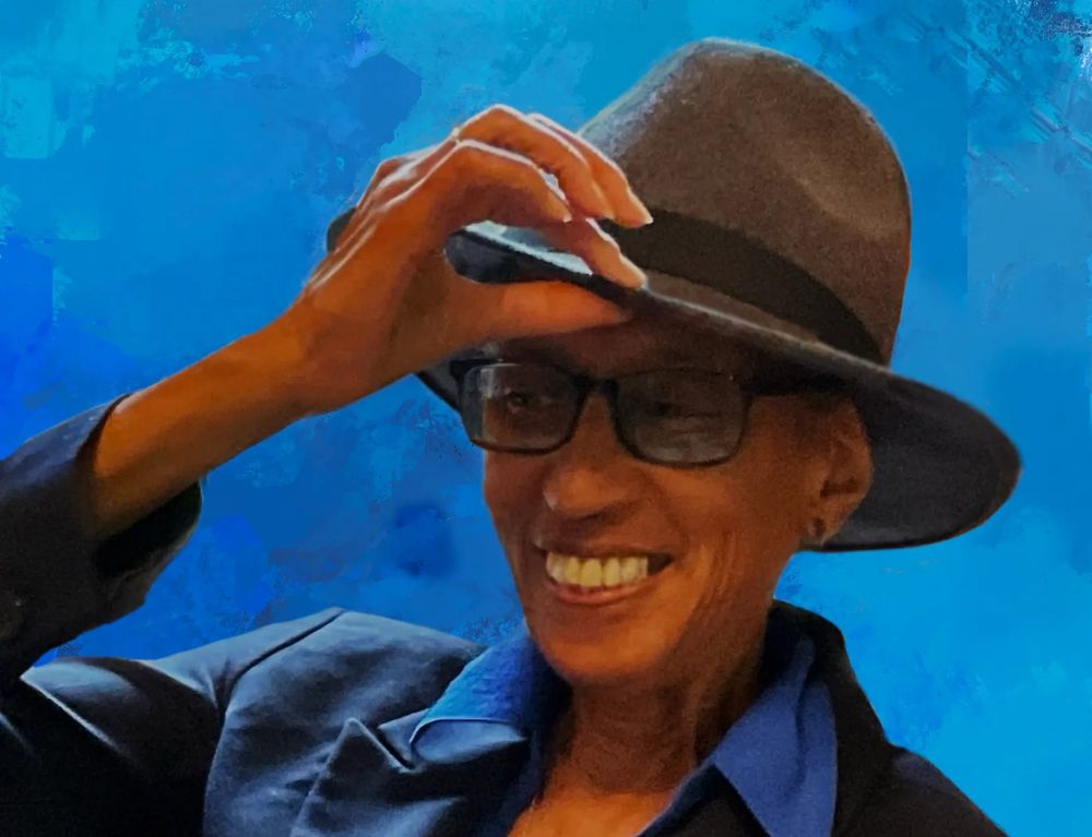 The writer and Tolkien scholar Melanie Rawls, an African American woman in a blue button-up shirt, glasses with thick black rims, and a dapper fedora.