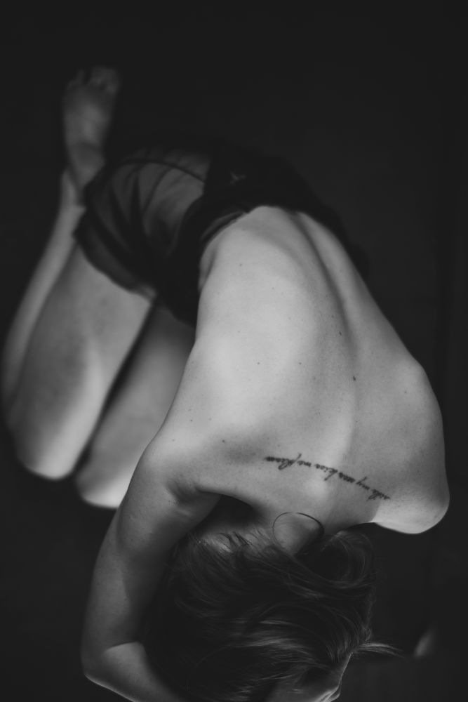 photo of a female model taken from above while she is kneeling on the floor and leaning forward.