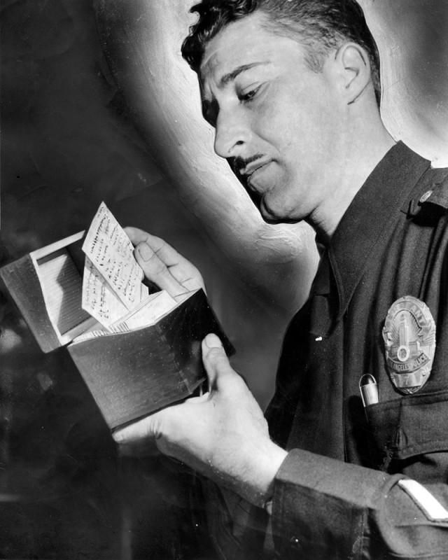 Photograph caption dated May 8, 1948 reads, "Vice Sgt. C. W. Bates examines name-cards confiscated in raid on alleged house of ill-repute."