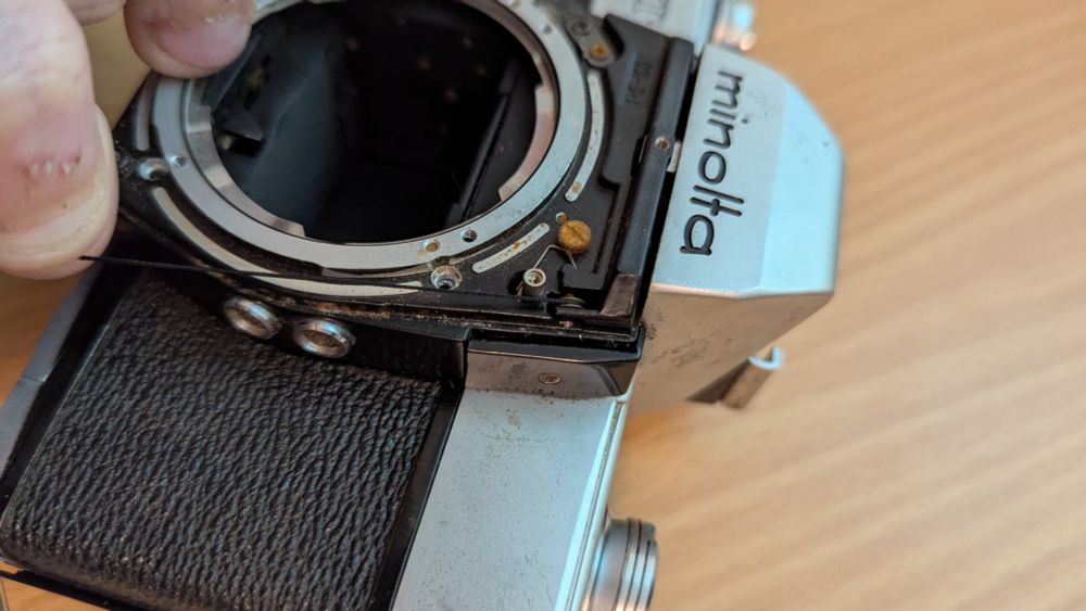 Minolta SRT-101 with bayonet and faceplate removed showing return system for aperture ring. 