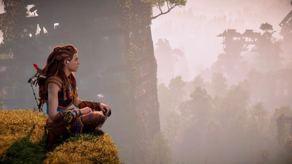 Aloy meditating by sitting at the edge of a tall abandoned building, with more abandoned buildings in the background. Trees can also be seen, and the layers of trees and building gradually disappears into the mist in the distance.