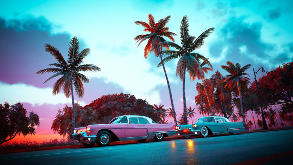 Two classic cars lined up with the sunset behind 