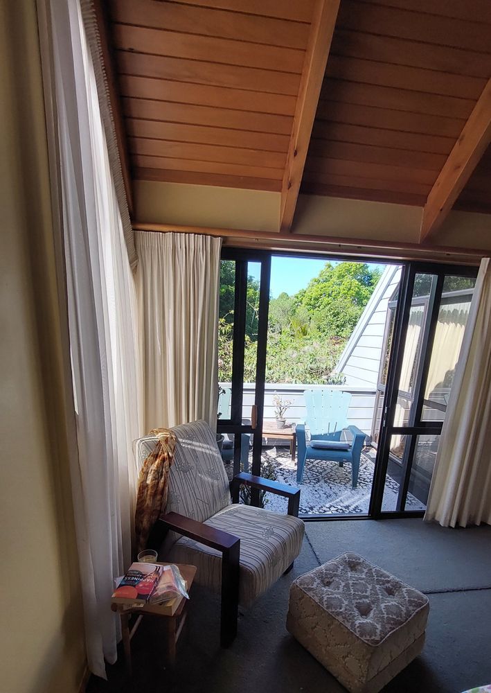 Armchair and footstool looking out over balcony to blue sky and trees