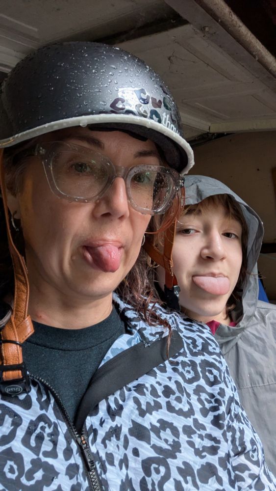 A soggy woman & a soggy child stick their tongues our at the camera. 