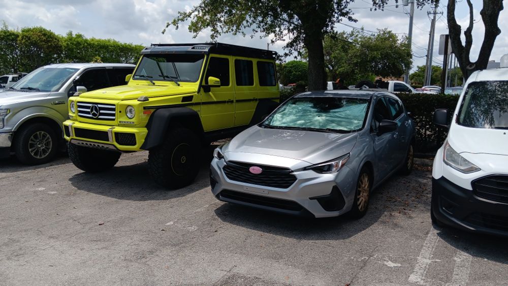 Base Subaru Impreza next to the Mercedes G wagon 4x4 in highlighter yellow. 