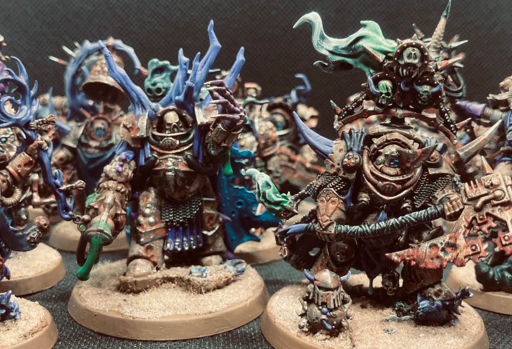 Death Guard terminator characters in front of other marines, bone/brown armour, corroded metal and sandy bases.