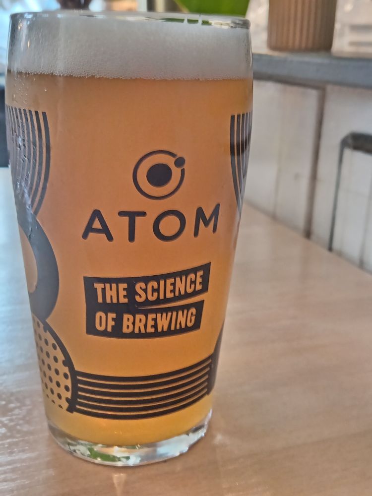 Pint of beer with "atom the science of brewing" on the glass