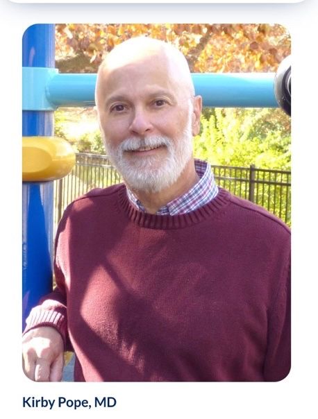 A professional looking Nazi in a Maroon sweater with white hair and beard  standing on a playground