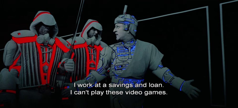 An individual being ushered by security guards exclaims "I work at a savings and loan. I can't play these video games."