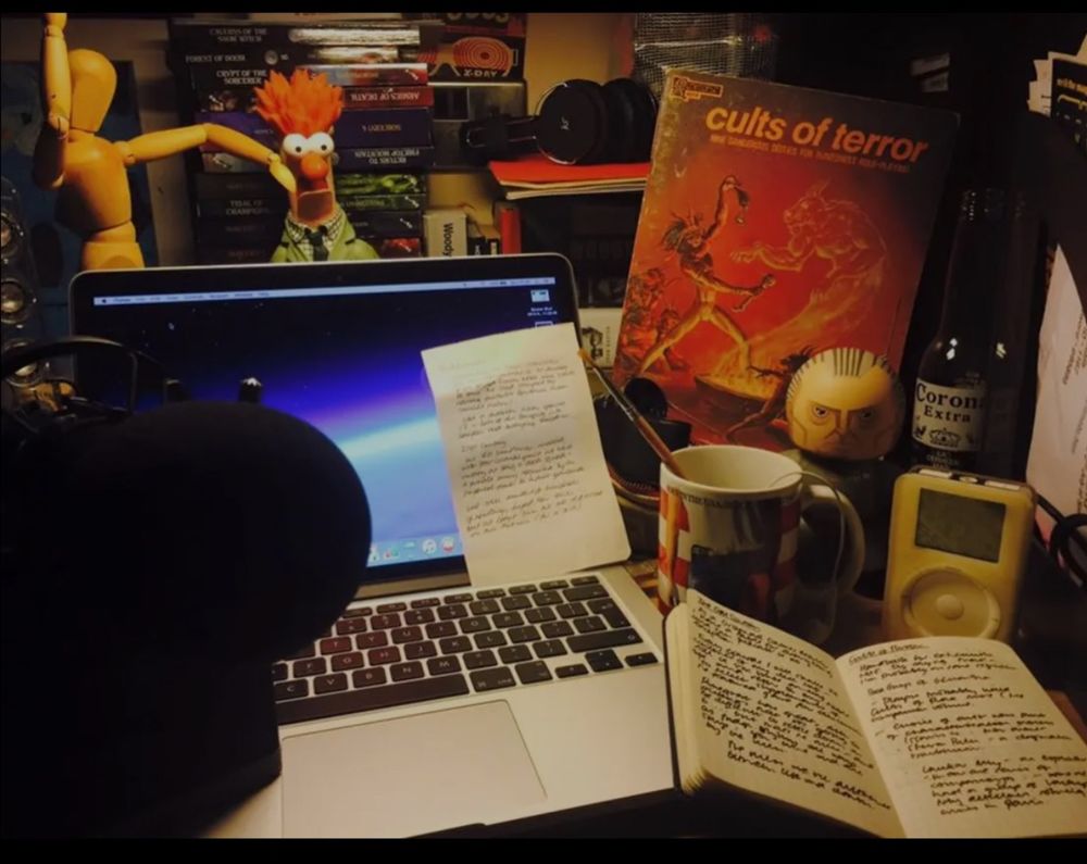 A laptop on a messy desk featuring RuneQuest Cults of Terror