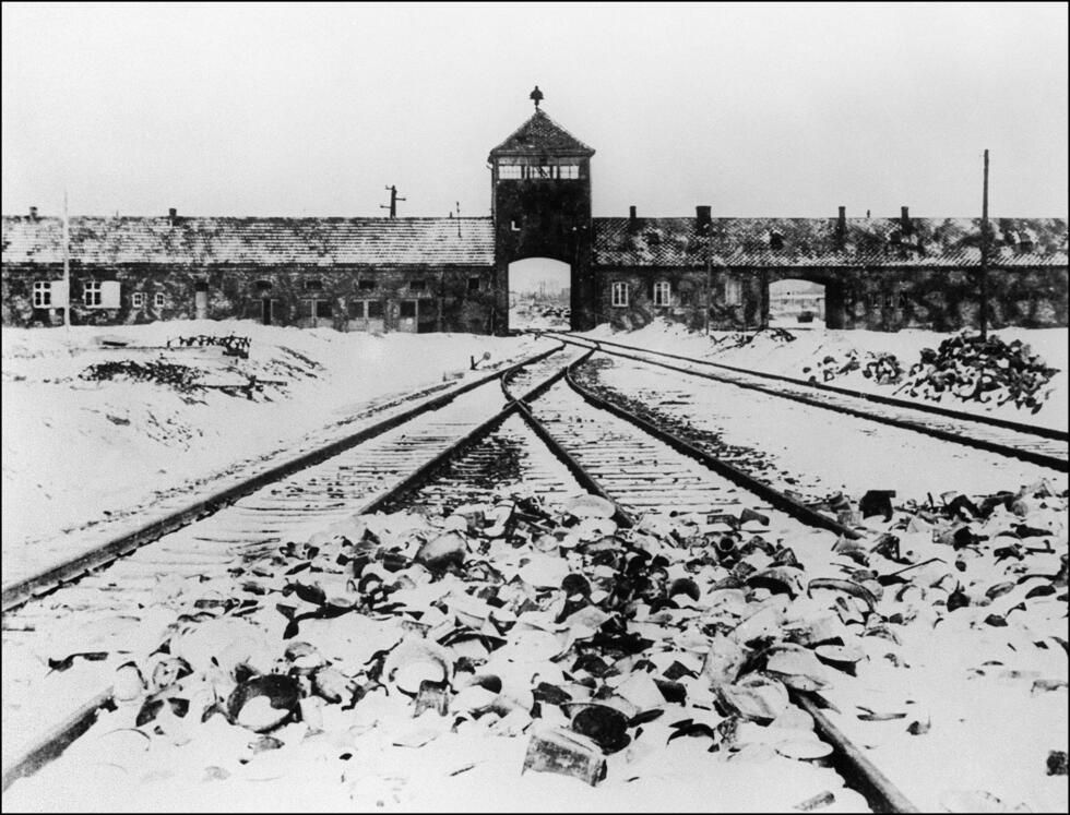 Photo of shoes piled up on the railroad line leading to the entrance of the Birkenau Camp in Auschwitz.