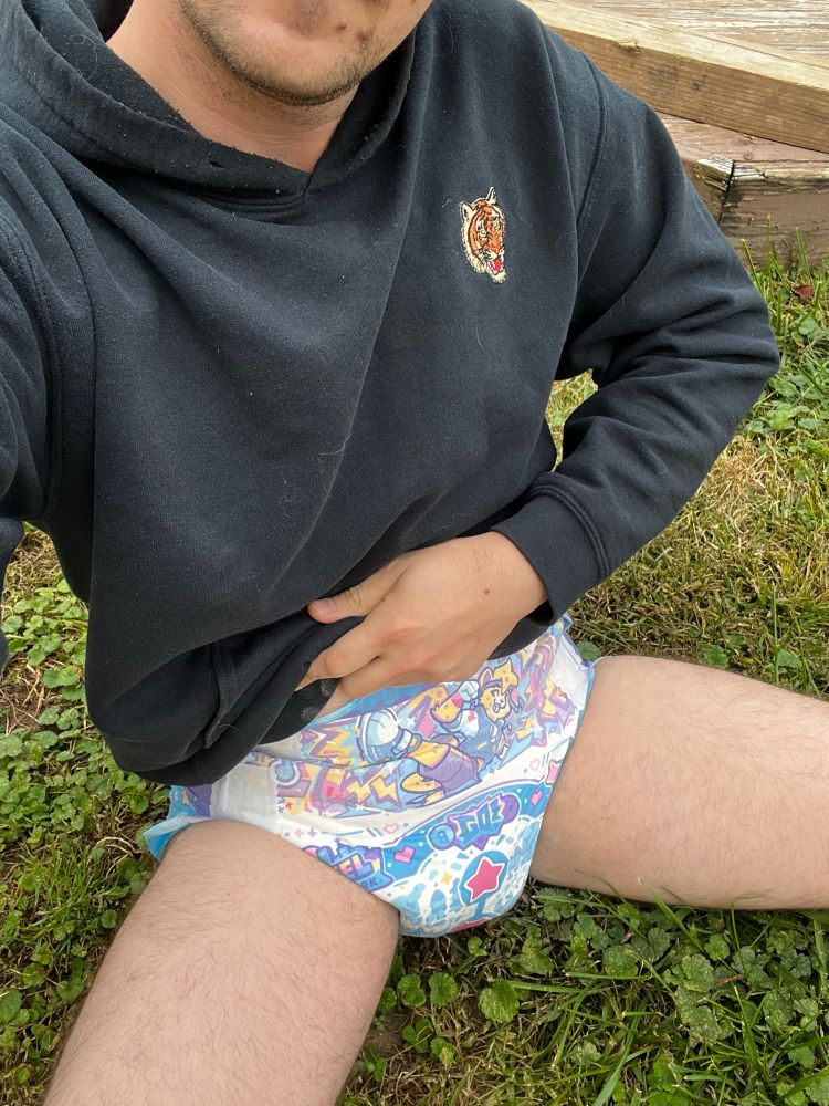 Momby sitting in the grass in a pixel pals and a hoodie