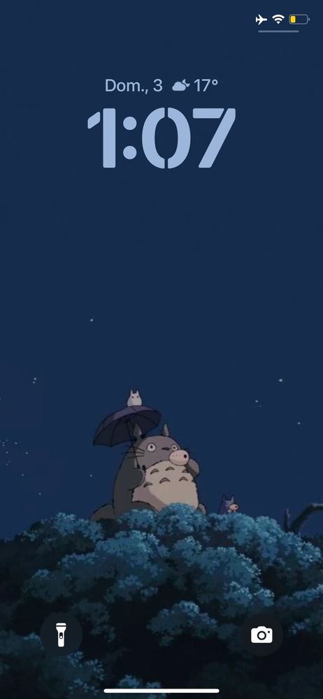 Uma captura de tela da minha tela de bloqueio, onde está o personagem Totoro, em cima de uma grande árvore segurando um guarda chuva preto, com uma criaturinha fofa em cima e ao lado e ao fundo um lindo céu estrelado. 