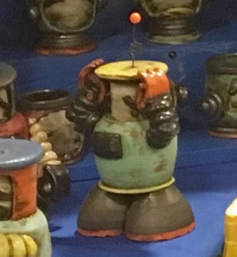 Ceramic robot sculpture holding head in stressful pose