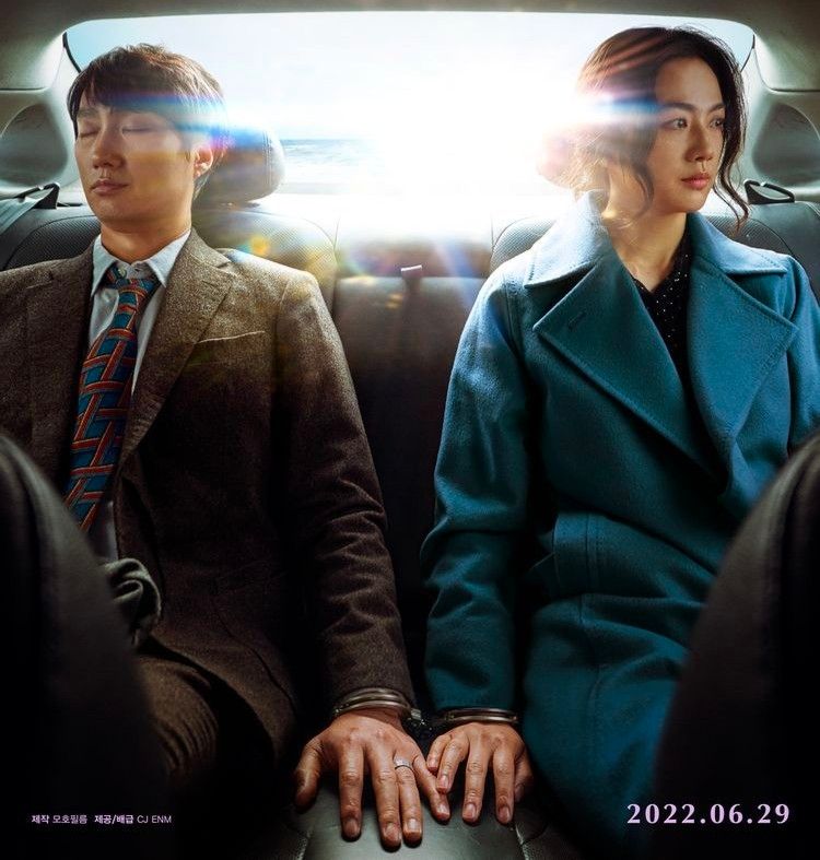 Policier et une jeune femme menottés à l'arrière d'une voiture. L'homme semble assoupi et la femme regarde par la fenêtre. Ils ne se regardent pas mais leurs mains se frôlent. Scène extraite du film "Décision to leave".