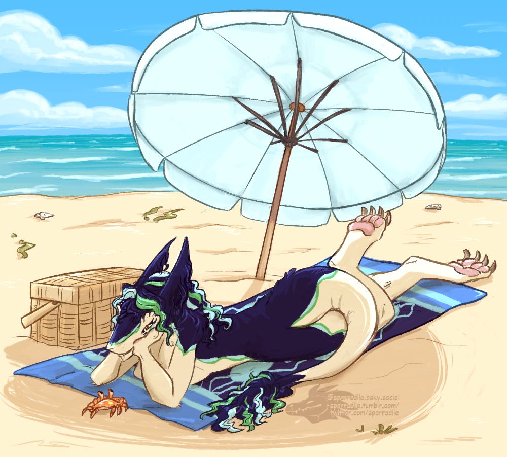 A blue and sand colored sergal laying on a beach towel, shaded by an umbrella and watching a crab scuttle by. 