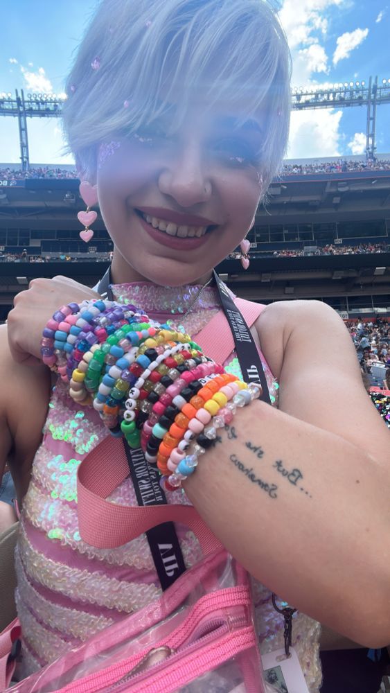 me inside Mile High Stadium wearing tons of friendship bracelets on my arm in preparation for The Eras Tour Denver