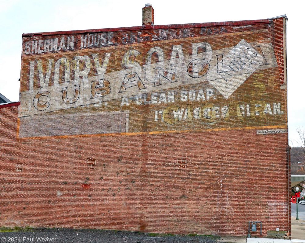 Faded painted signs for Ivory Soap and Cubanola Cigars are seen on a brick building