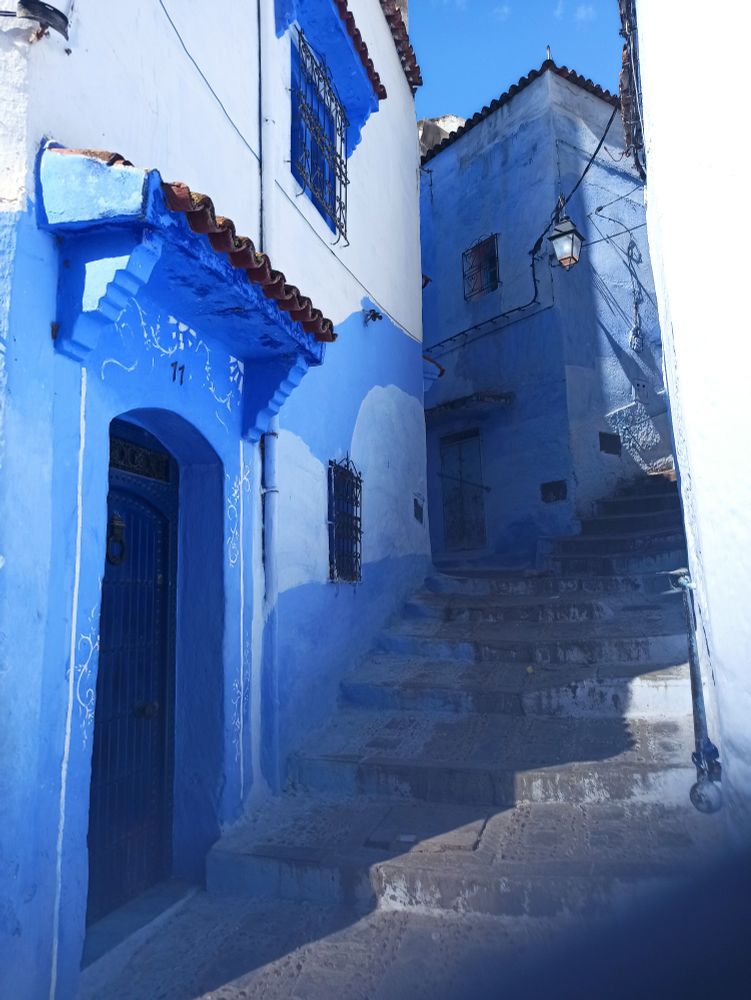 Treppenstufen in einer engen Gasse aufsteigend zwischen zwei blau gestrichenen Häusern in der Stadt Chefchaouen in Marokko
