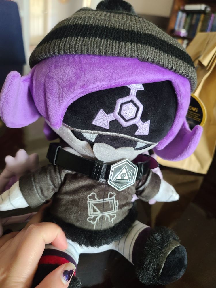 solver uzi plush sitting on a table with a pleather choker on 