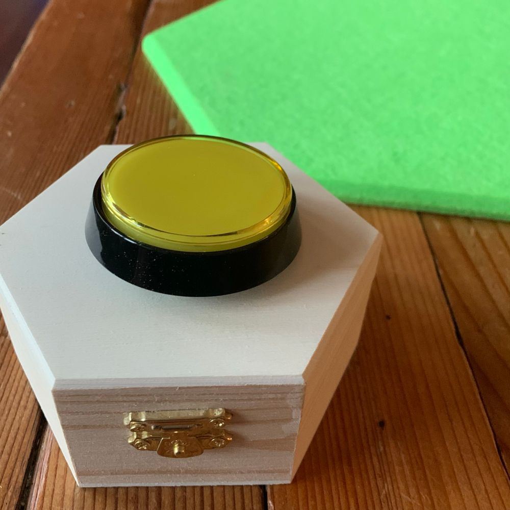 Button sitting on top of a hexagonal wood box
