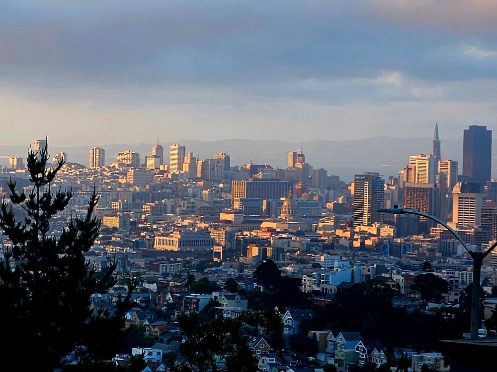 View of downtown San Francisco California, looking East from Diamond Heights neighborhood - golden sunlight on Pyramid Building, San Francisco City Hall and US Mint, among others