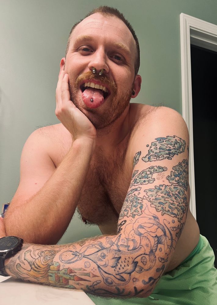 Guy with piercings  and tattoos sticking out his tongue