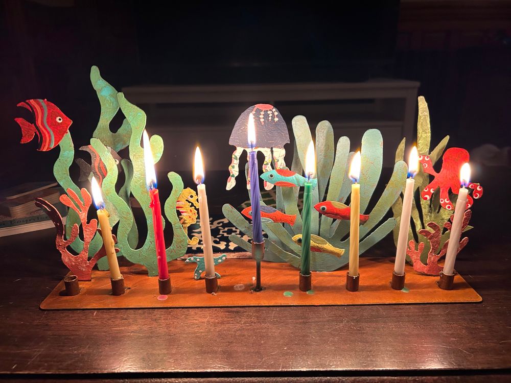 A menorah lit for the 7th night of Hanukkah. The menorah is a 3D undersea scene. 