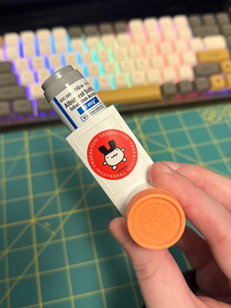 pic of my hand holding my albuterol inhaler, showcasing a mimitchi sticker on the front
