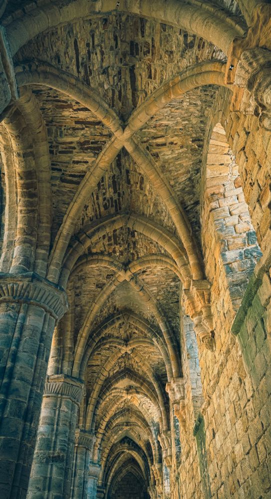 Shot downwards of one of the side aisles of the abbey featuring the vaulted ceilings made of stone. 