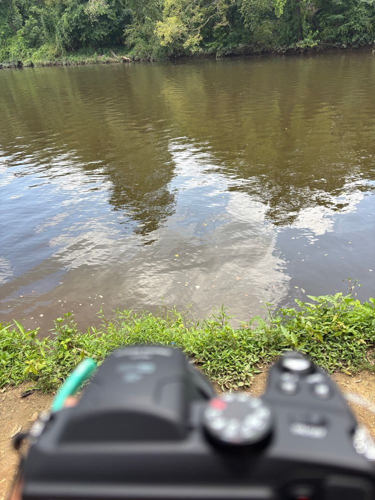 Sunnie holding a Kodak camera in front of the Appomattox river 