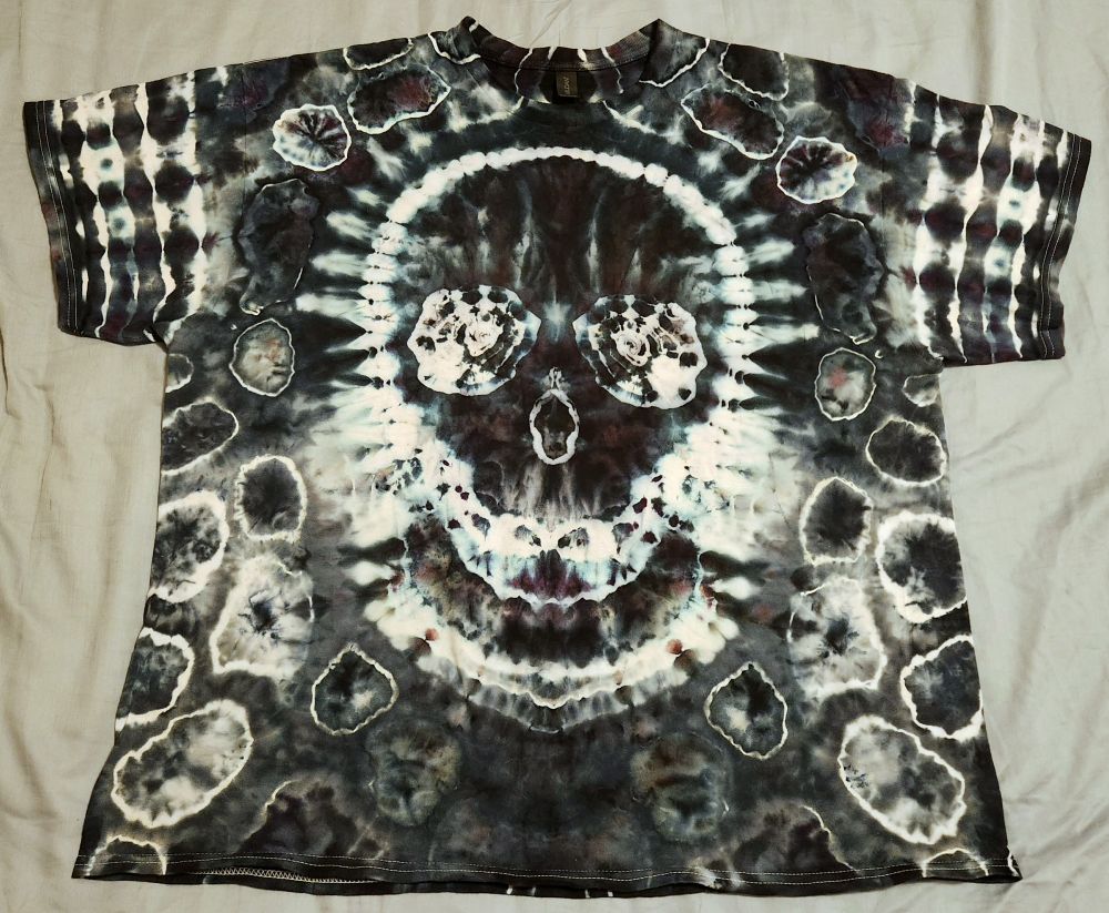 The front of a mostly black tie-dye shirt with a big skull in the middle made of white lines