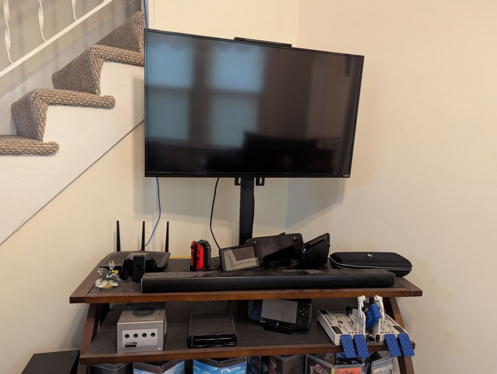 A TV on a TV stand featuring, among other things, a Wii U, Switch, Switch 2, and Steam Deck
