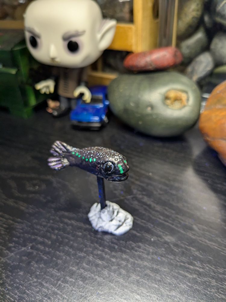 Clay model of an anglerfish, with the glow in the dark spots glowing green 