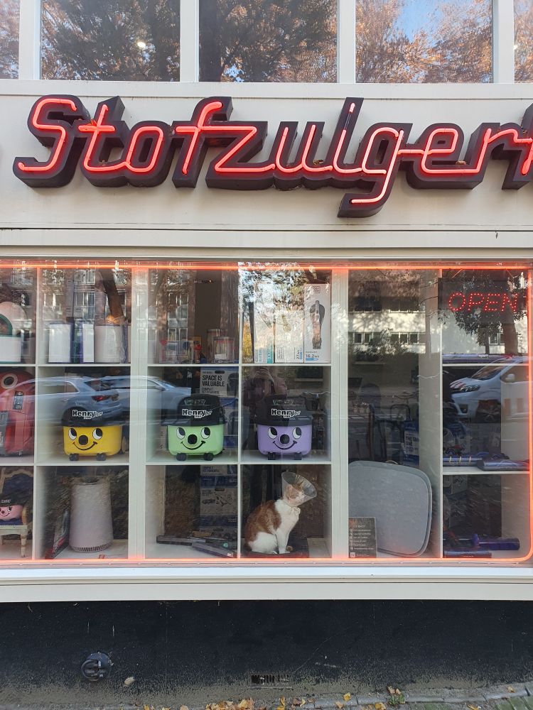 Gevel van de stofzuigerkoning. Allemaal stofzuigers in de etalage en een kat met een kap om
