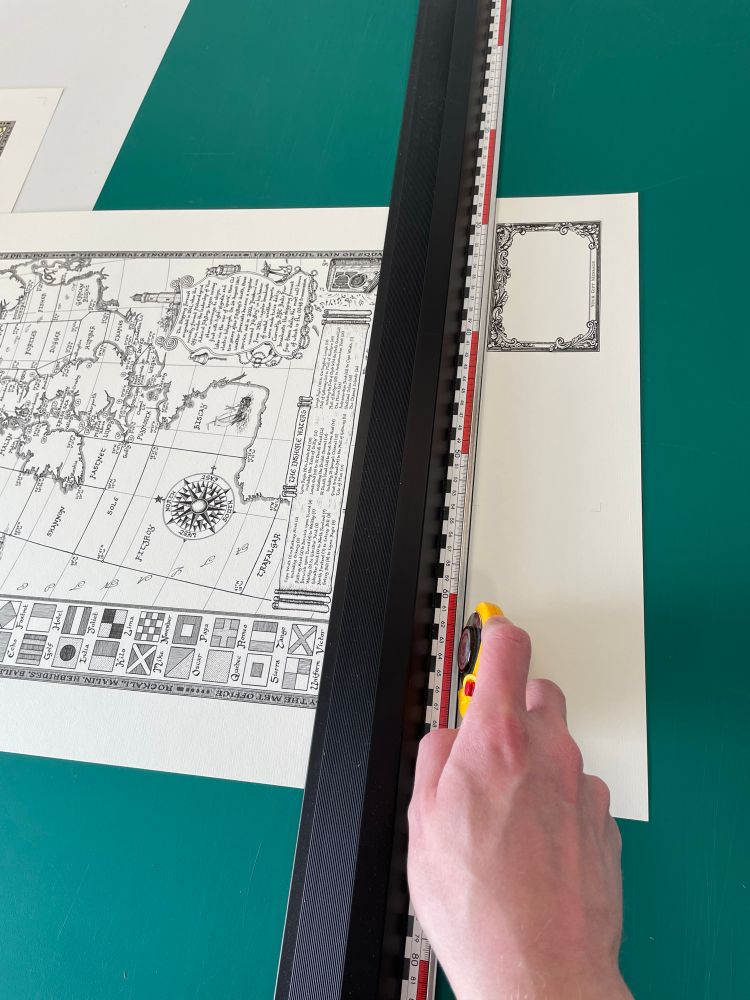 Hand trimming a map print of the Shipping Forecast drawn by Manuscript Maps, using a rotary cutter against a straight edge.