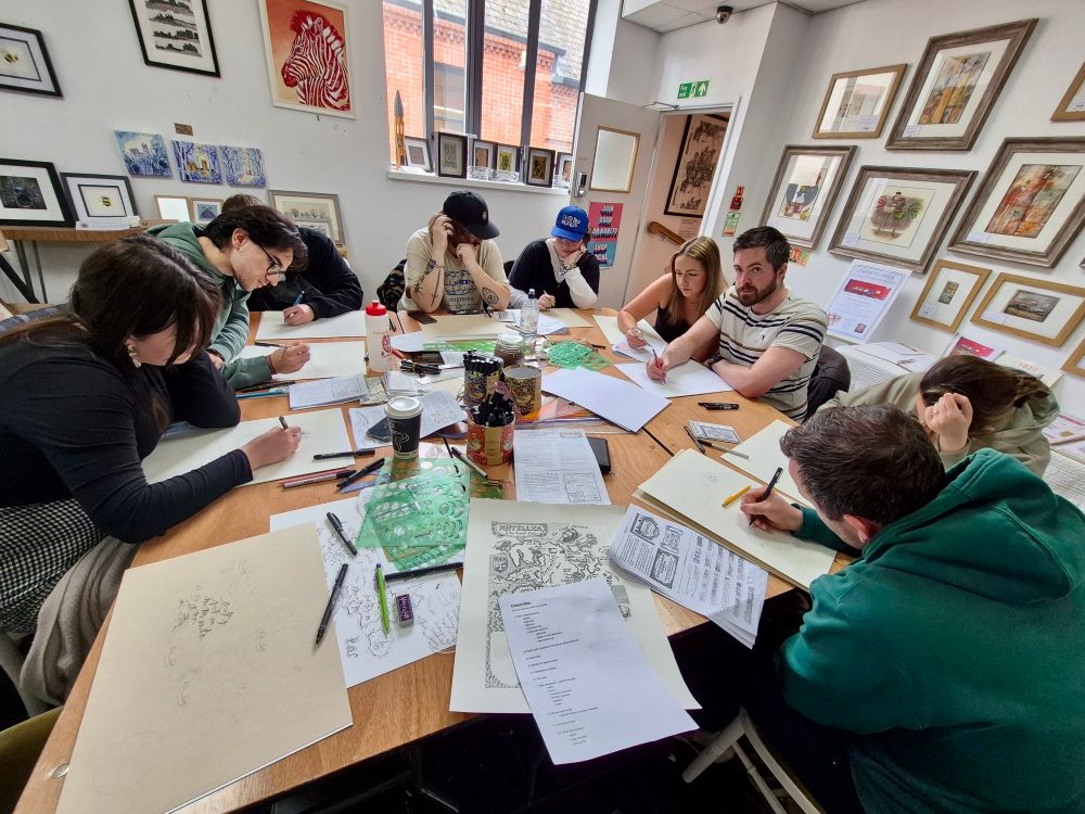 Photo of several adult students drawing maps by hand at a workshop by Manuscript Maps.