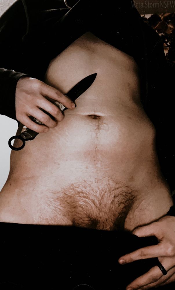 Metal standing pulling down his pants to show off. While holding a knife near his chest. 