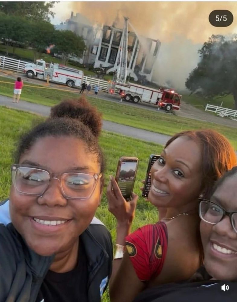 3 amazing young women stand smiling infront of the burning remains of what was the last standing slave plantation. 