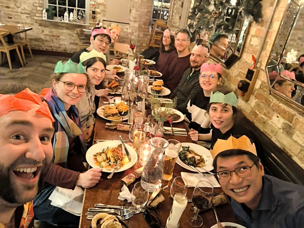 We are sitting around a busy, long dinner table, all wearing color paper crowns and smiling