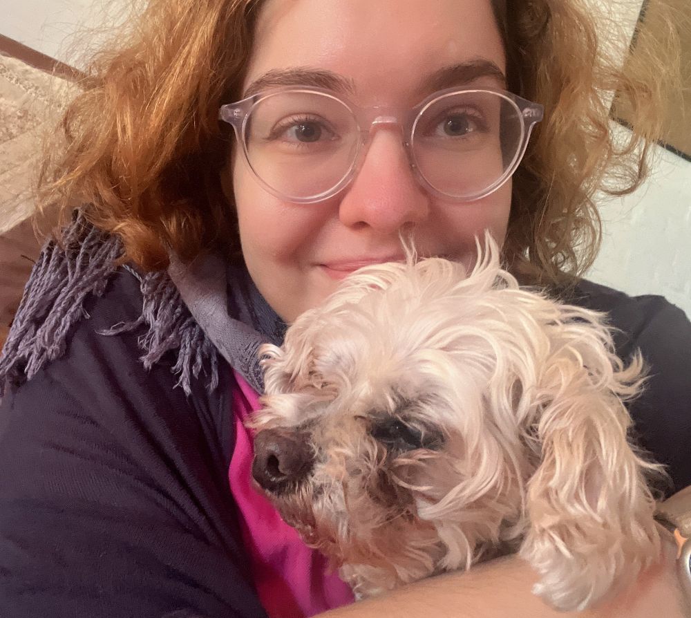 Me smiling and hold my my old shaggy looking maltipoo dog, Hobbes, in my arms