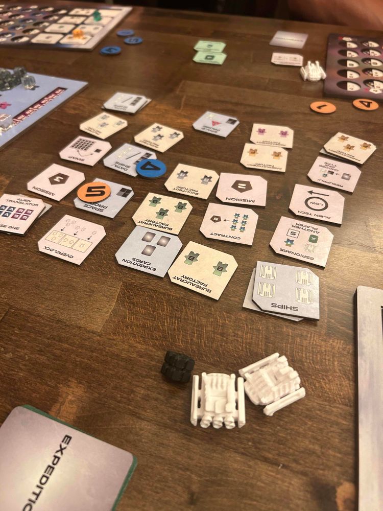 A game of Ago Sector in progress. Tiles arranged in a 5x5 grid. A few dual-layer boards are visible in the background and periphery. 