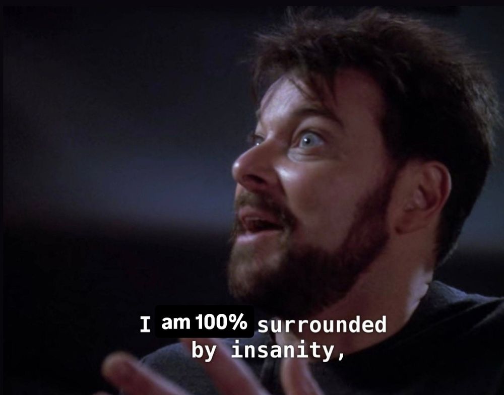Riker, from Star Trek TNG The Next Generation, is looking off to the side with a wide-eyed, wild expression. His hair is messy and his mouth is open as he speaks. His dialogue, which has been crudely edited, is captioned: "I am 100% surrounded by insanity"