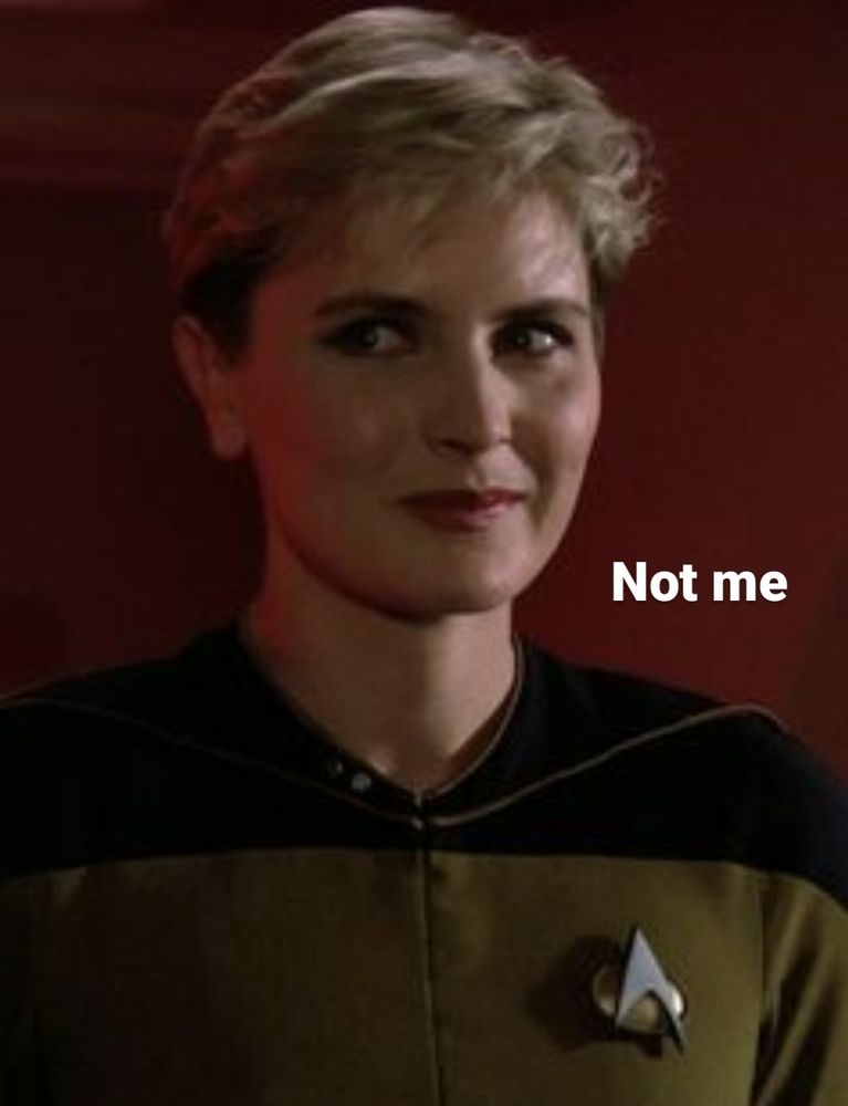 Tasha Yar from Star Trek TNG The Next Generation. She's looking to the side with a sky little smile playing on her lips. She's saying "Not me."