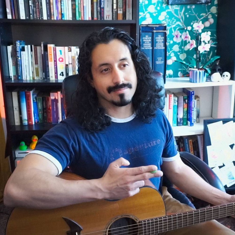 musician twitch streamer with his guitar in a book filled room