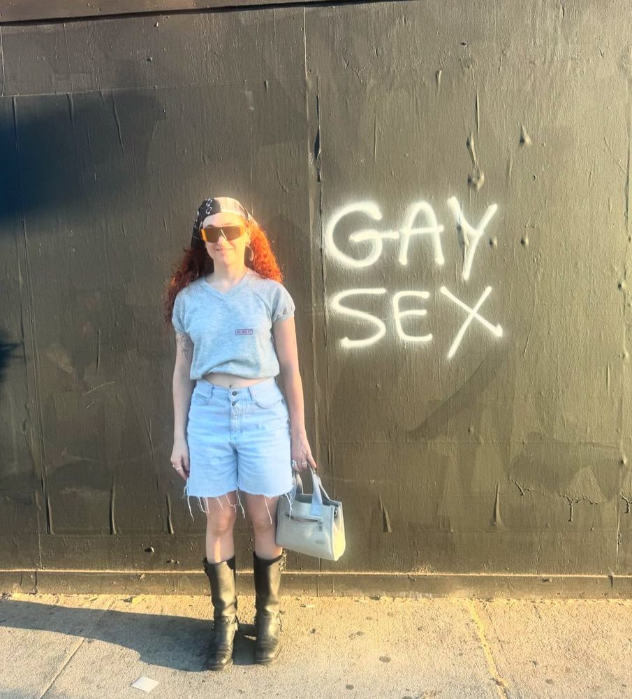 chappell roan in front of graffiti that says “gay sex”. 