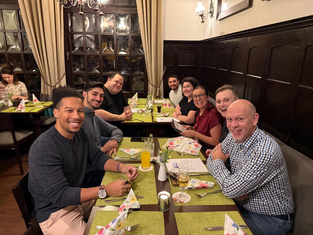 Group of people smiling and sitting at a dining table in a traditional restaurant setting.
