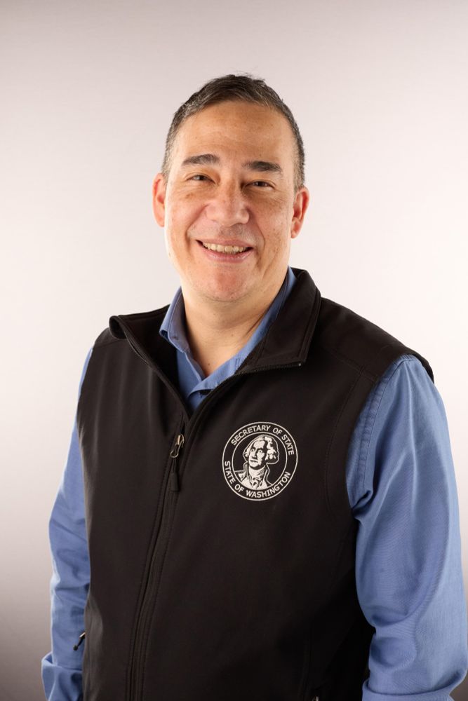 Person wearing a vest with the logo of the "WA Office of the Secretary of State" smiling at the camera.
