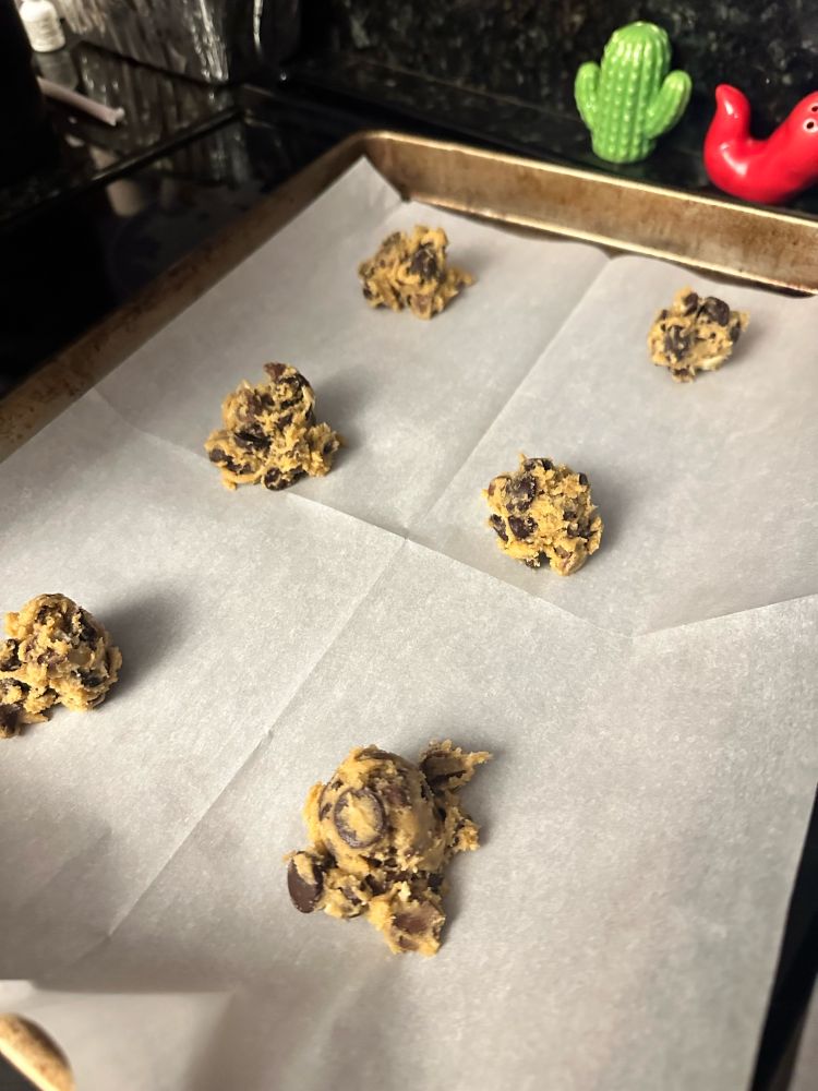 Balls of cookie dough on a cookie sheet ready to go in the oven 